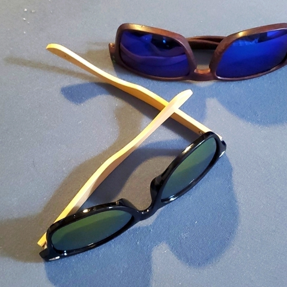 2 pair of sunglasses both are new. One has bamboo arms, one blue tint.
